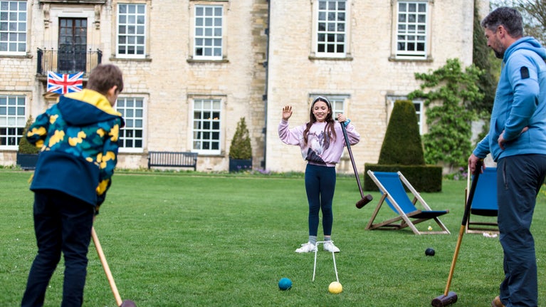 Family playing croquet on front lawn at Nunnington Hall in spring